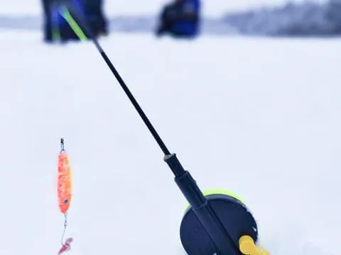 Ice Fishing on Frozen Lake by Arctic SnowHotel