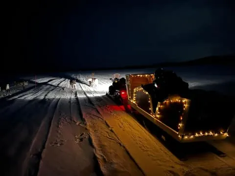 Night-time experience in a snowmobile-pulled sleigh in Ivalo
