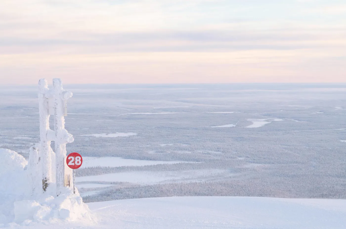 Snow-covered trail marker on the open fell at Ylläs